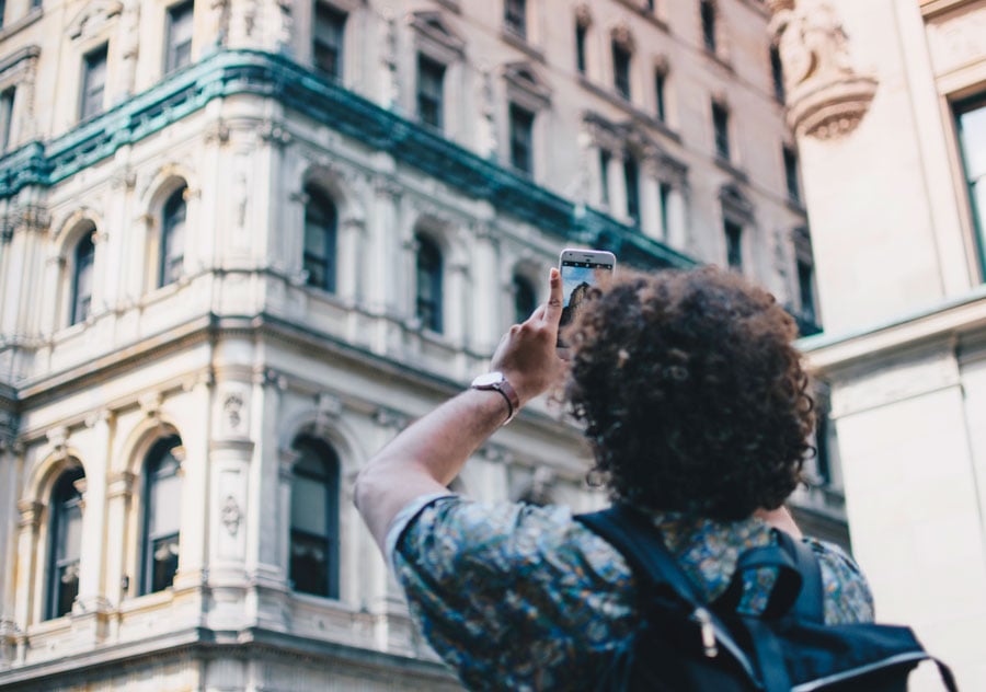 Teen taking a picture of a building on his phone