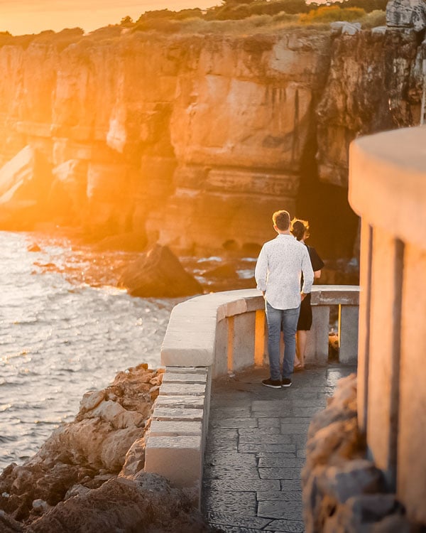 Couple on a balcony overlooking the waves and rocky cliffs